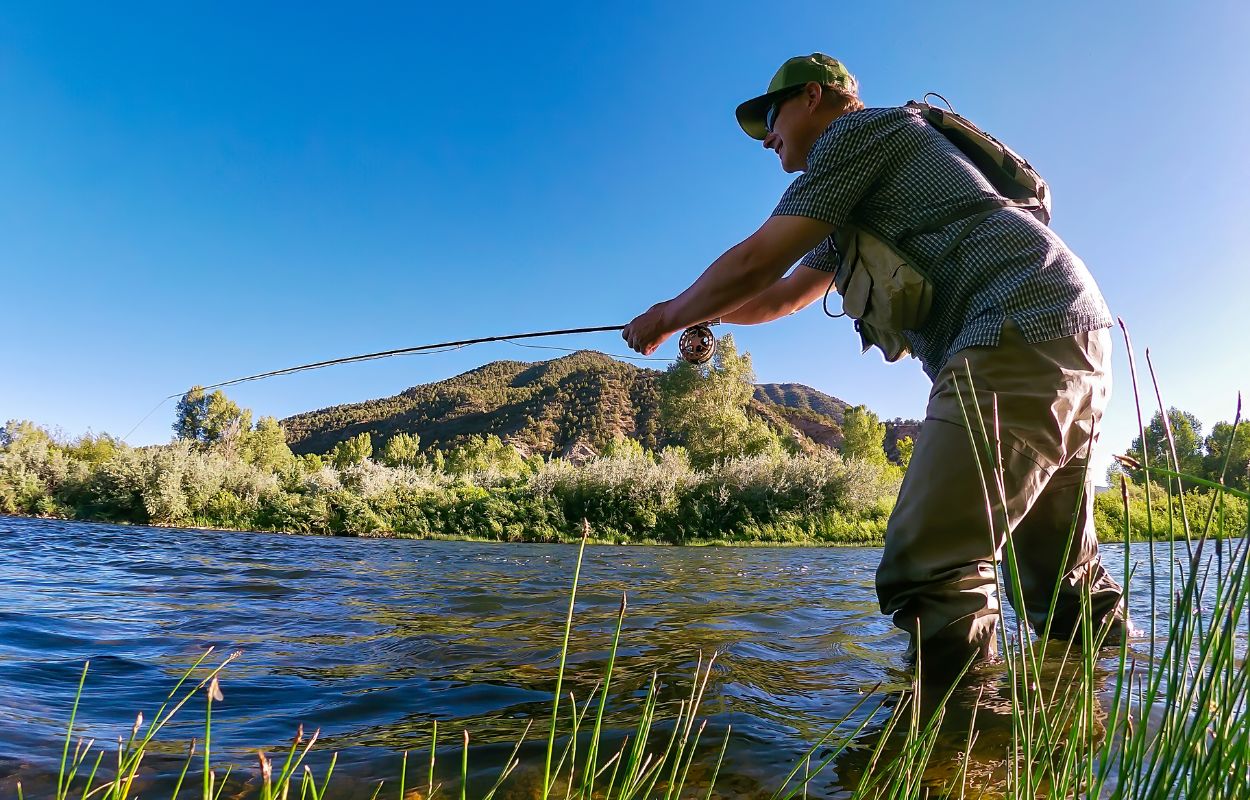 angler standing in a river with mountain in the background